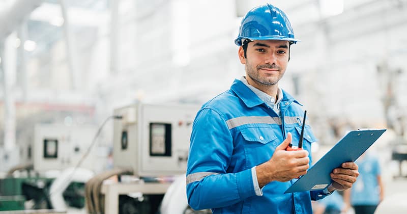 Male worker with thumbs up and machinery behind him