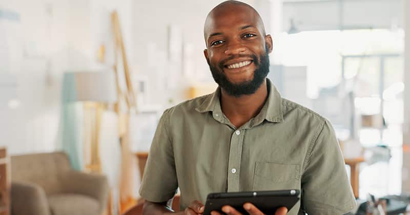 Happy business man in an office holding tablet
